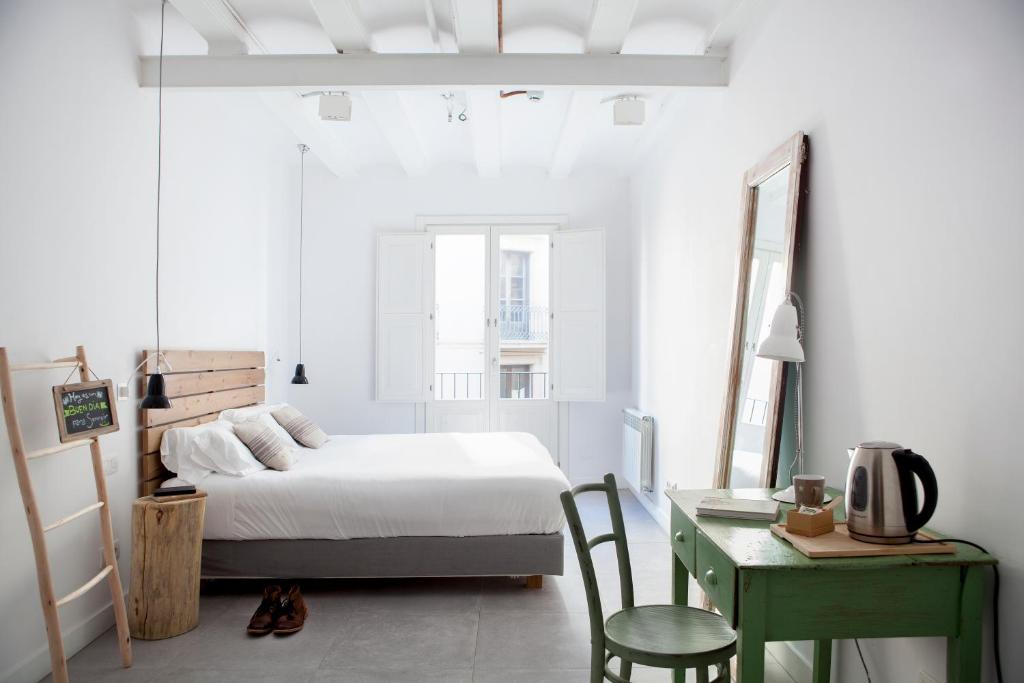 
a bedroom with a bed, chair, and a window at Eco Boutique Hostal Grau in Barcelona
