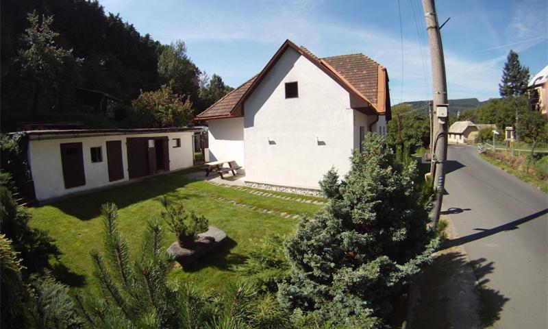 una pequeña casa blanca con un patio de hierba al lado de una casa en Penzion pod vejmutovym lesom, en Kremnica