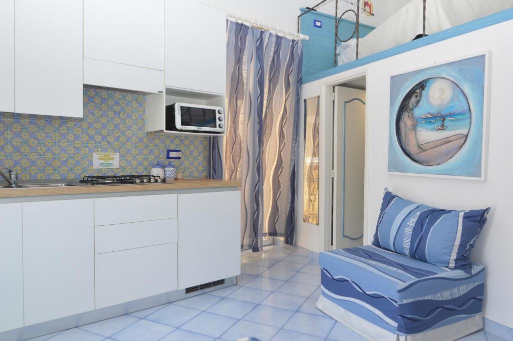 a kitchen with white cabinets and a blue chair at Central Studio Capri in Capri