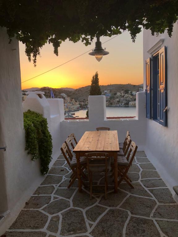 a wooden table and chairs on a patio with the sunset at Plesner House, Symi Greece in Symi