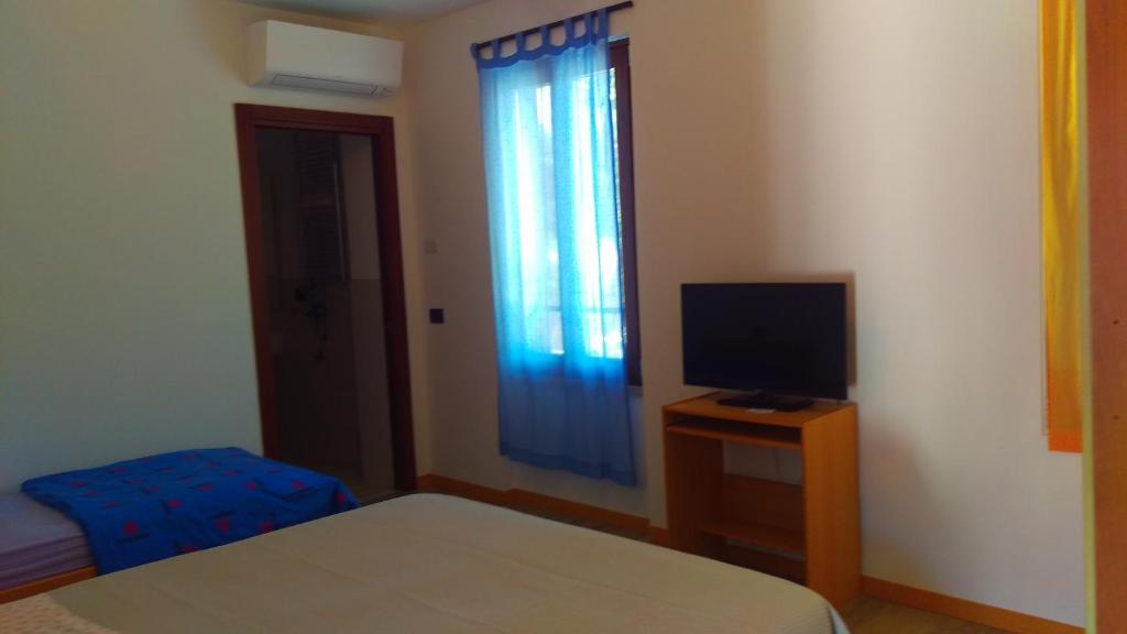 1 dormitorio con 1 cama, TV y ventana en Al terminal en Somma Lombardo