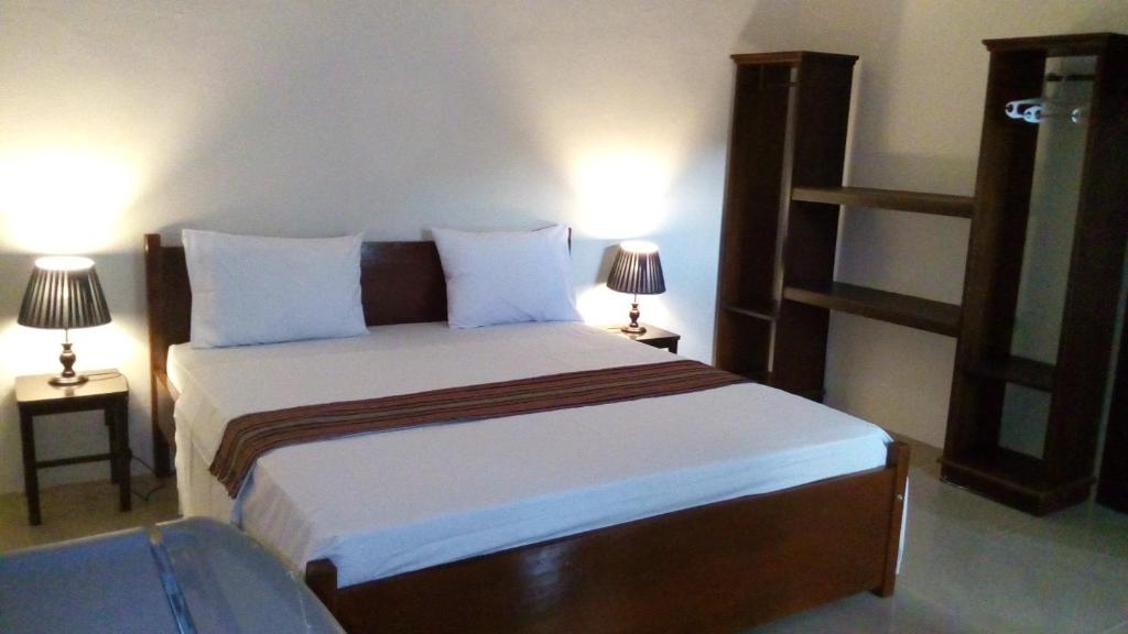 a bedroom with a large bed with two lamps at Rasti Homestay in Kuta Lombok