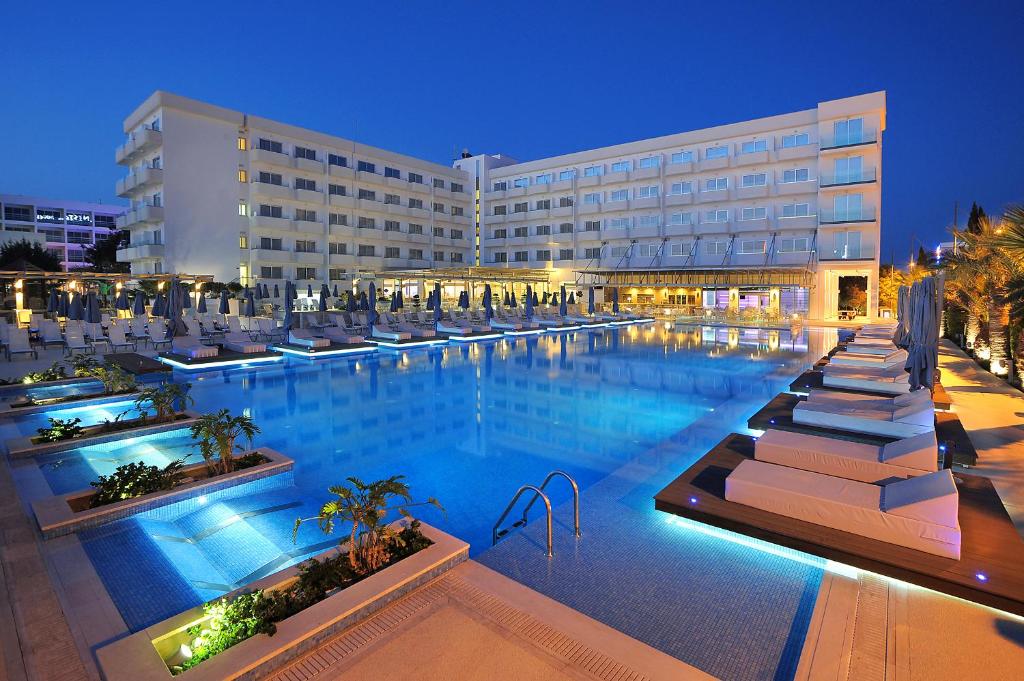 a hotel with a large swimming pool at night at Nestor Hotel in Ayia Napa