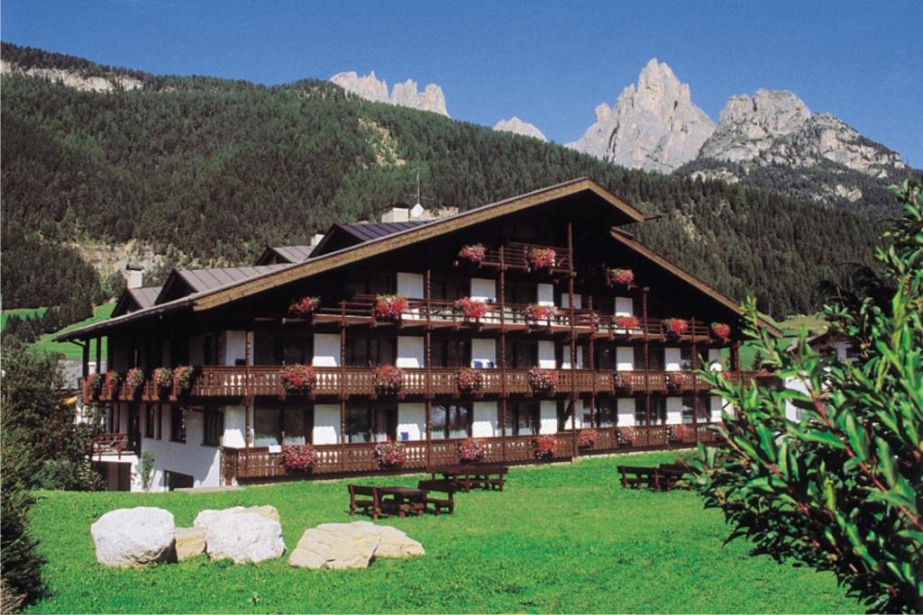 un grande edificio con panchine di fronte a una montagna di Residence Anda a Pozza di Fassa