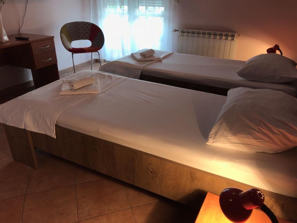 two large beds in a bedroom with a chair at Guest house IVO in Split