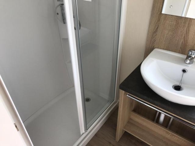 bagno con doccia e lavandino bianco di Bude Holiday Mobile Home a Bude