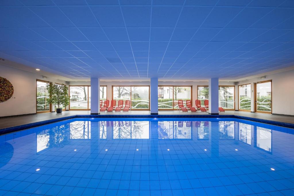 - une grande piscine dotée de carrelage bleu et de fenêtres dans l'établissement Hotel Masatsch, à Caldaro