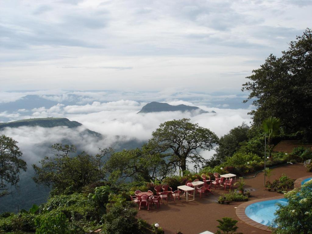 ein Restaurant mit Blick auf die Berge und Wolken in der Unterkunft Lords Central Hotel in Matheran