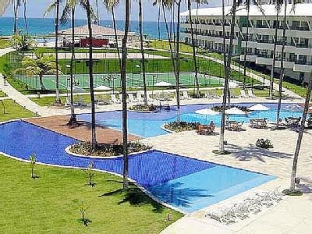 Condominio Ancorar Flat Resort في بورتو دي غالينهاس: اطلالة علوية على مسبح به نخيل