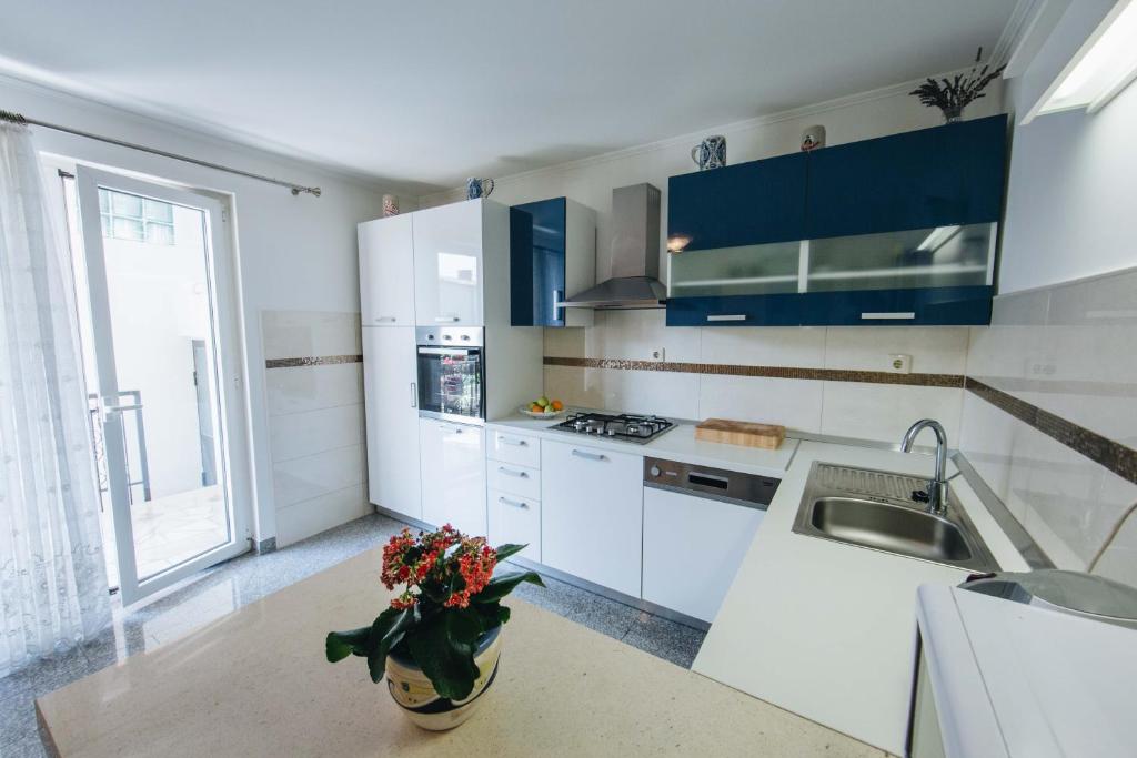 uma cozinha branca com armários azuis e um vaso de flores em Apartment Danica em Split
