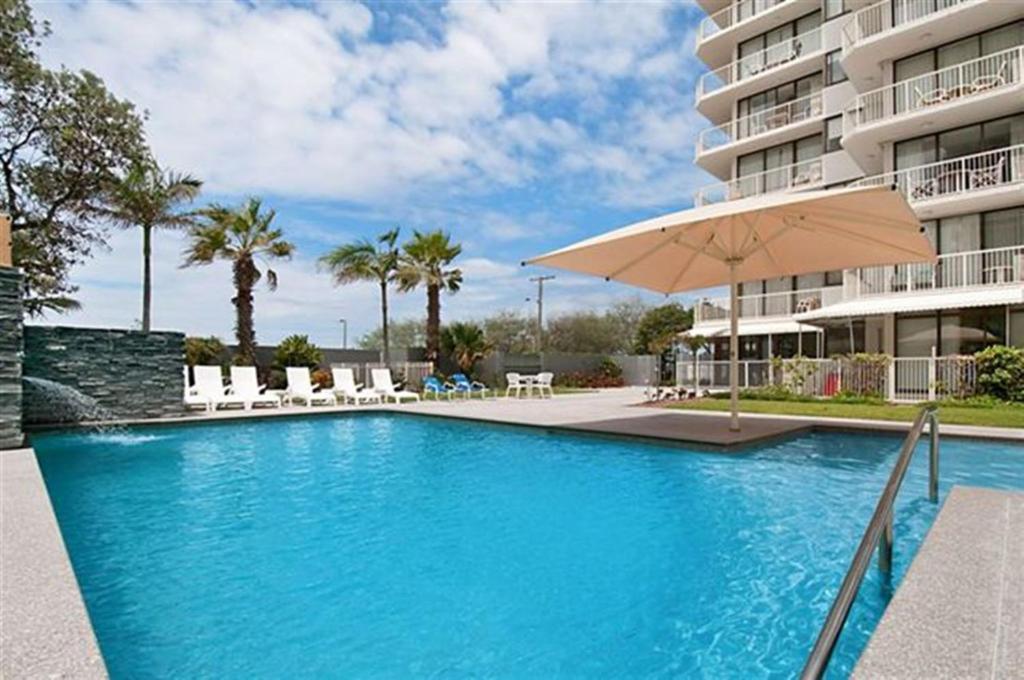 a swimming pool with an umbrella next to a building at Boulevard Towers in Gold Coast