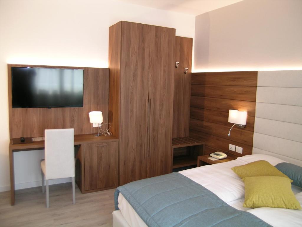 a bedroom with a bed and a desk with a television at Hotel Belvedere in Venice-Lido