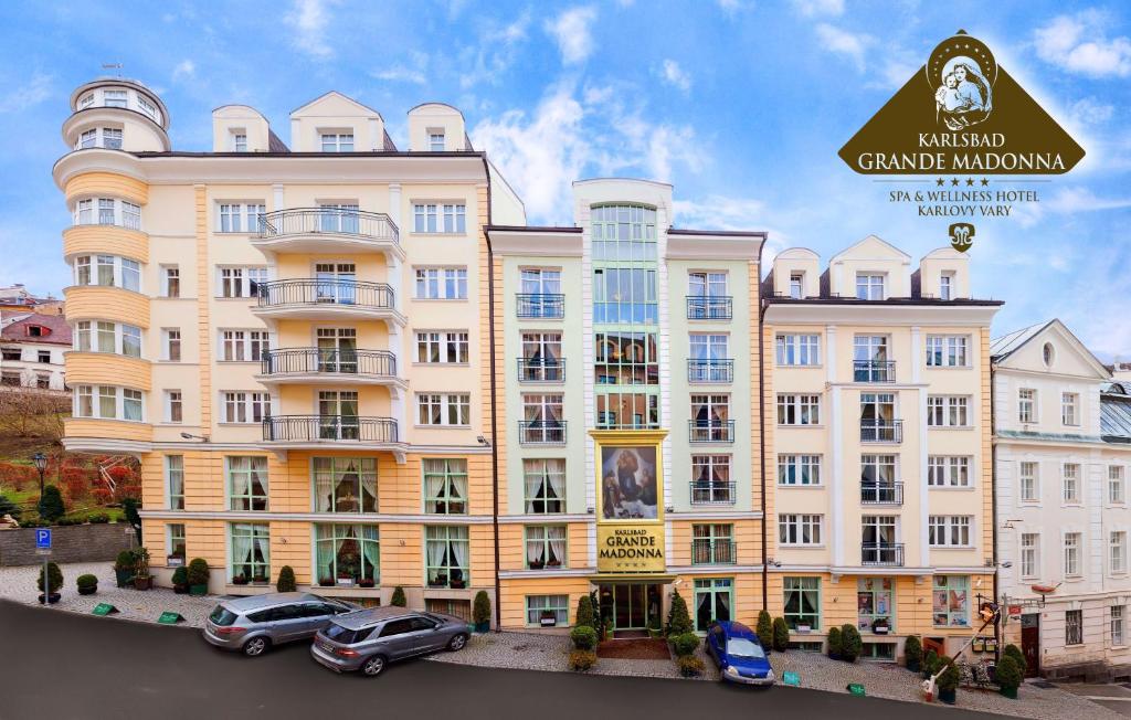 a large building with cars parked in front of it at Karlsbad Grande Madonna in Karlovy Vary