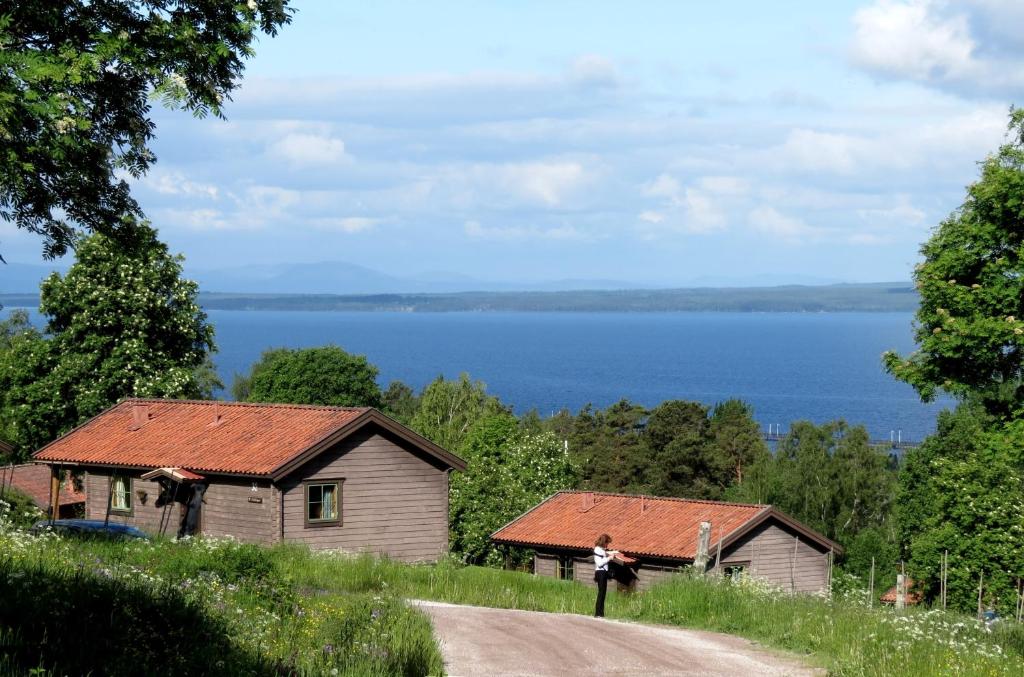 a woman standing on a dirt road next to two buildings at Fyrklöverns Stugby in Rättvik