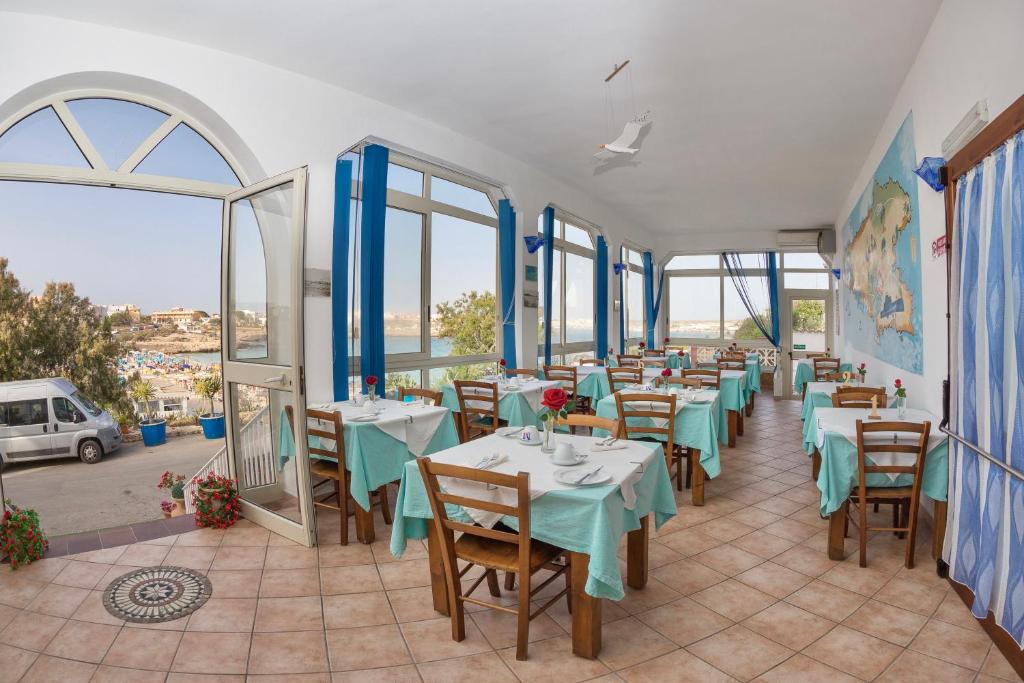 a restaurant with tables and chairs and windows at Hotel Giglio in Lampedusa