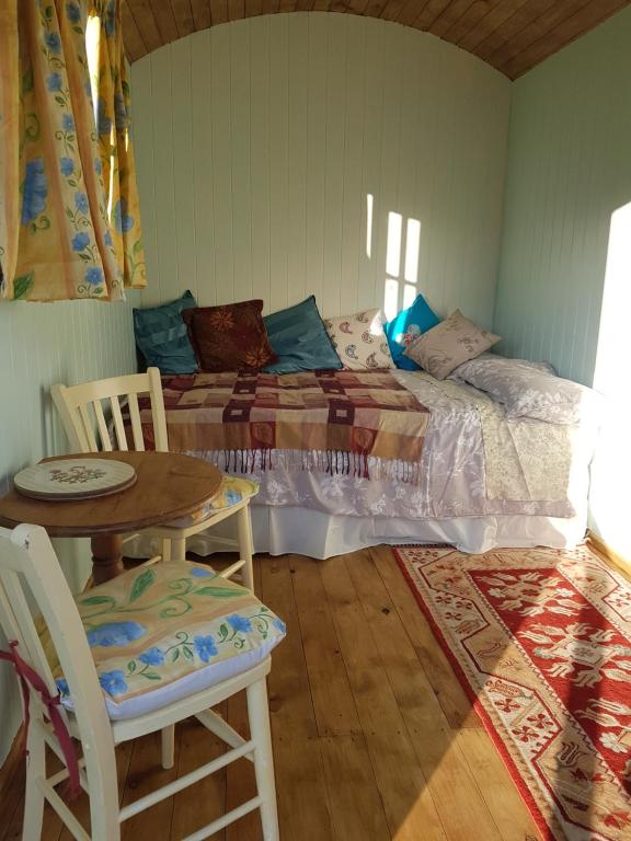 Schlafzimmer mit einem Bett, einem Tisch und Stühlen in der Unterkunft Shepherds hut Dolly wagon in Keswick