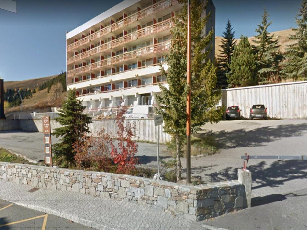 a building in front of a parking lot with a tree at Le Lauranoure - 205 in L'Alpe-d'Huez