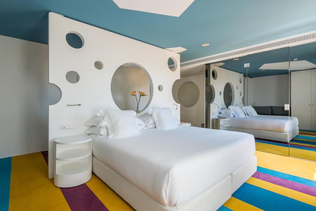 a bedroom with a large white bed and a mirror at Room Mate Pau in Barcelona