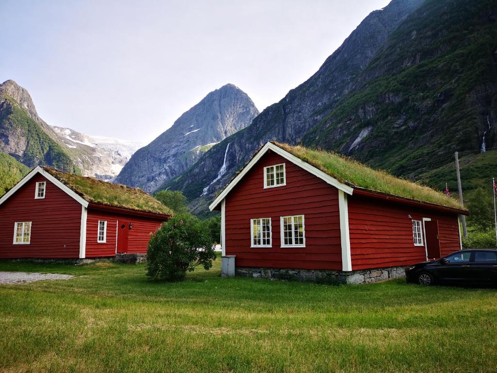 two red barns with a grass roof in front of mountains at Trollbu Aabrekk gard in Briksdalsbre