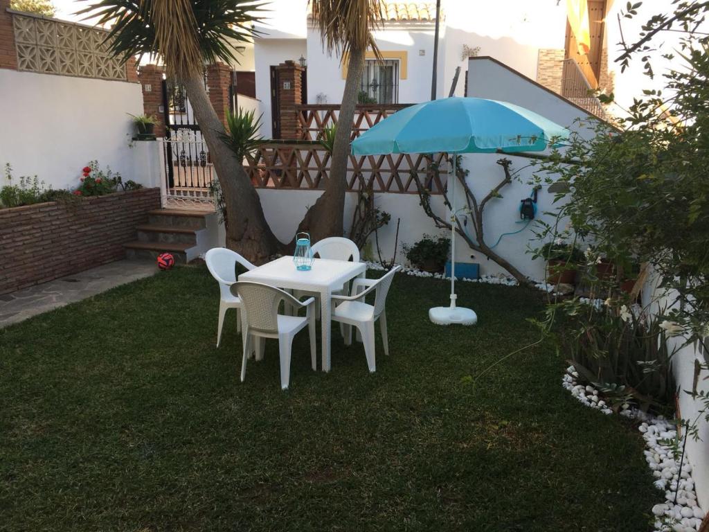 einen Tisch, Stühle und einen Regenschirm im Hof in der Unterkunft apartamento pueblo rocio 80 in Nerja