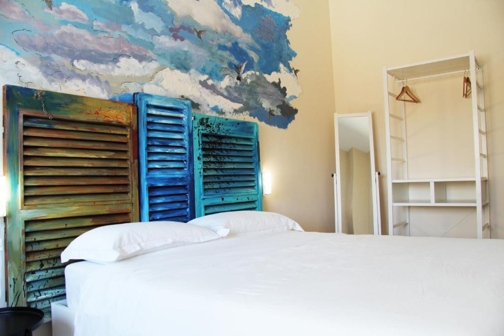 - une chambre avec un lit et une peinture de nuages dans l'établissement Urban Pop Bnb, à Catane