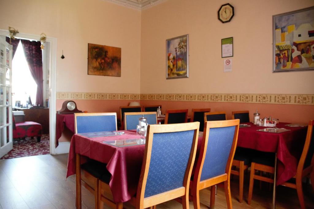 un comedor con mesas y sillas y un reloj en la pared en Bow Guest House en Reading