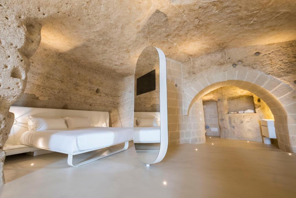 Aquatio Cave Luxury Hotel & SPA في ماتيرا: غرفة نوم مع سرير في غرفة مسورة حجرية