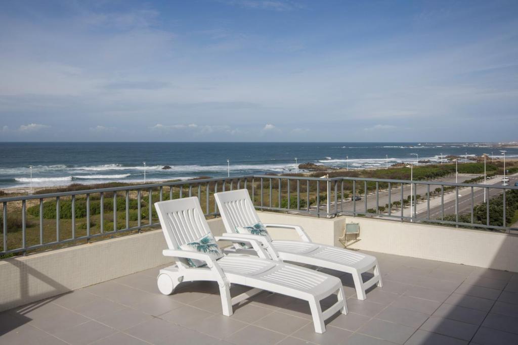 two white chairs sitting on a balcony overlooking the ocean at "Sea View"Loft in Vila do Conde