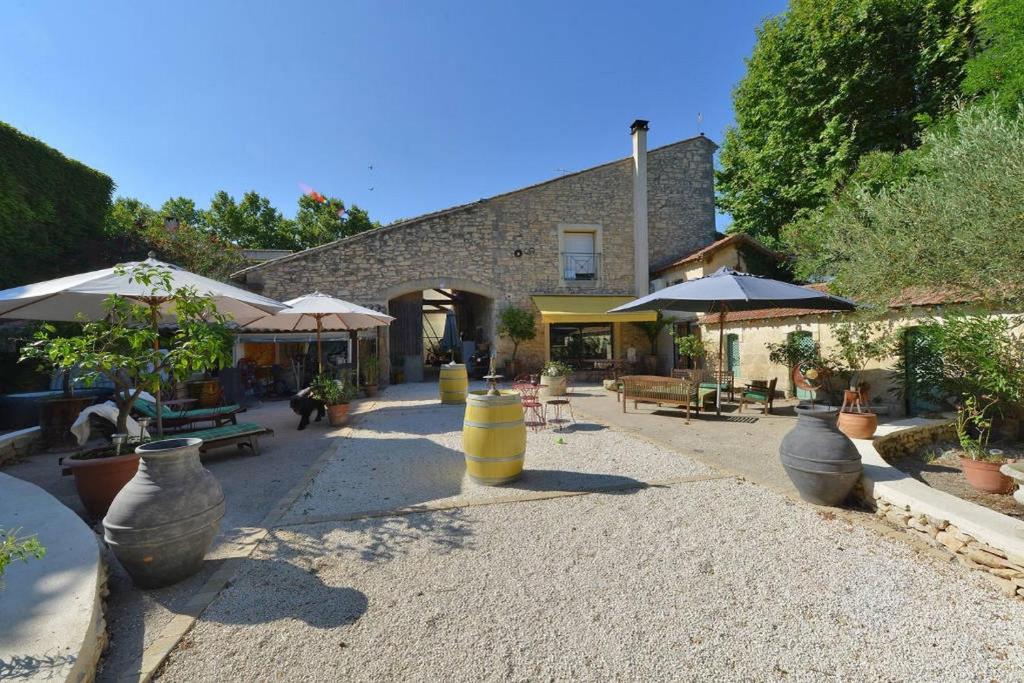 un patio con varios jarrones y sombrillas grandes en Le Clos des Aramons, en Bernis