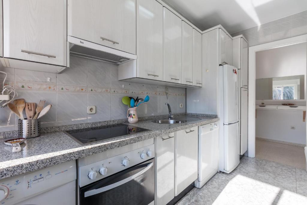 eine Küche mit weißen Schränken, einer Spüle und einem Kühlschrank in der Unterkunft TRIANA WITH FREE PARKING in Sevilla