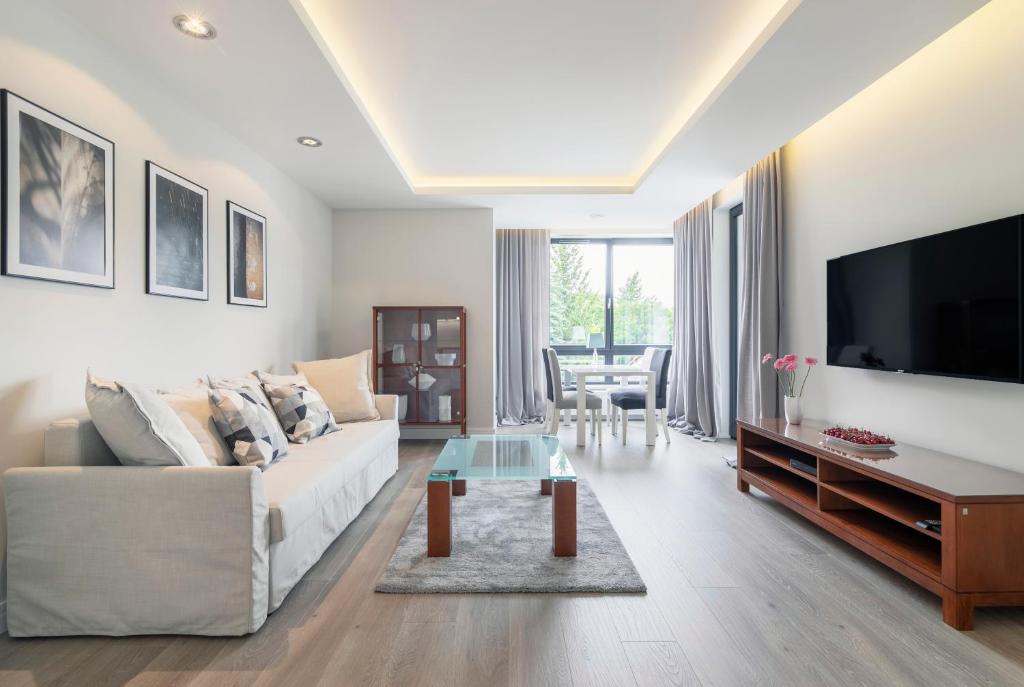 a living room with a white couch and a tv at Luxury Apartments - Okrzei Residence by Grand Apartments in Sopot