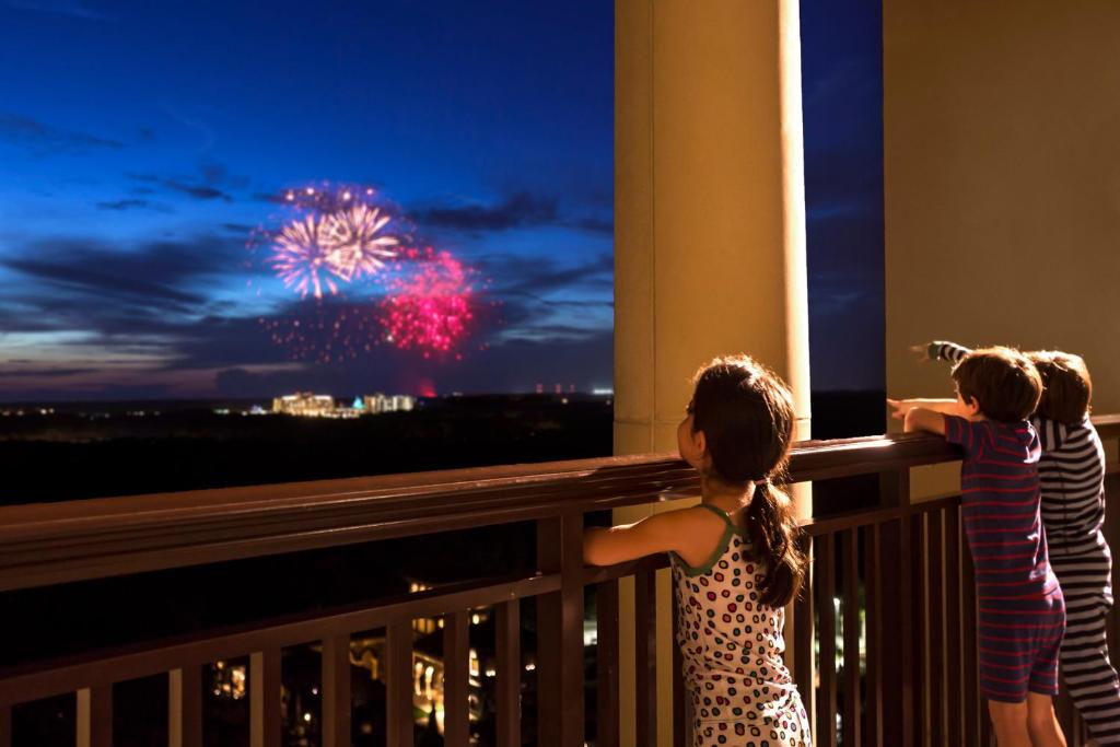two children standing on a balcony looking at a fireworks display at Four Seasons Resort Orlando at Walt Disney World Resort in Orlando
