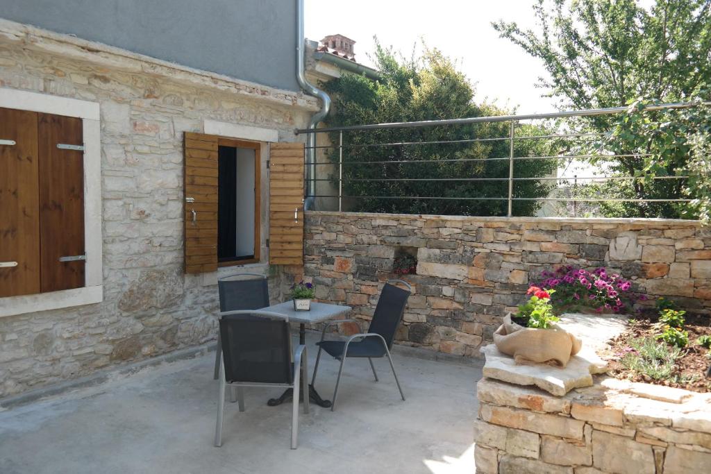 a patio with a table and chairs and a stone wall at Apartments Hedona in Pula