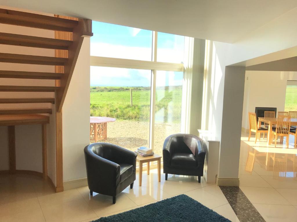 a living room with two chairs and a large window at Rannagh View in Liscannor