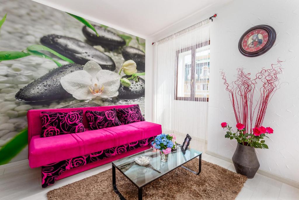 un sofá rosa en una sala de estar con una pintura en Guesthouse Korzo, en Rijeka