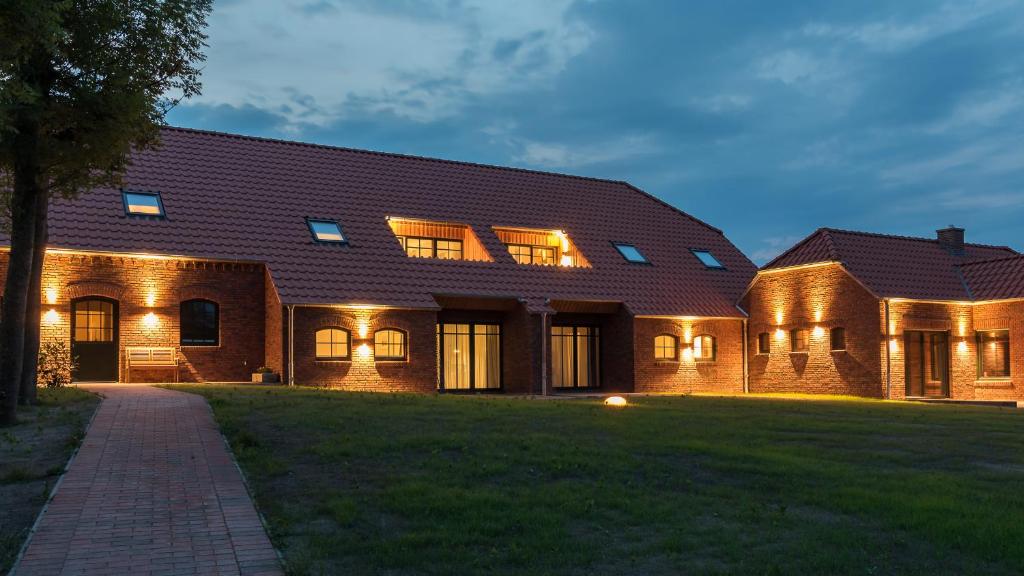 una gran casa de ladrillo con luces en el patio delantero en Hayungshaus Esens, en Esens