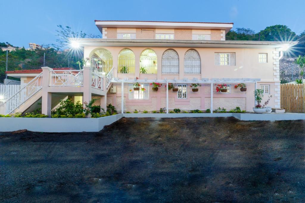 Cette grande maison blanche dispose d'une terrasse couverte et d'une cour. dans l'établissement Jasmine Inn, à Kingston