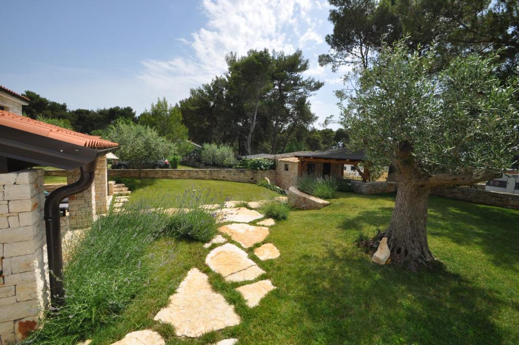 einen Hof mit einem Baum und einem Steinzaun in der Unterkunft Casa Fogoler Fažana in Peroj