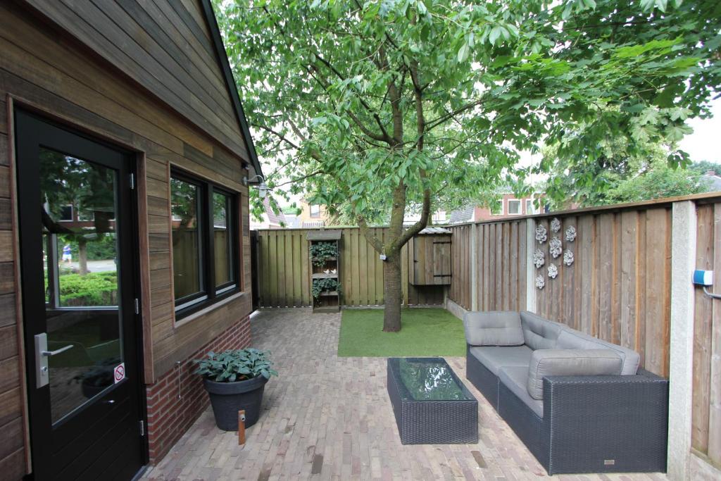 un patio con un sofá y un árbol en B & B Chawe, en Enschede