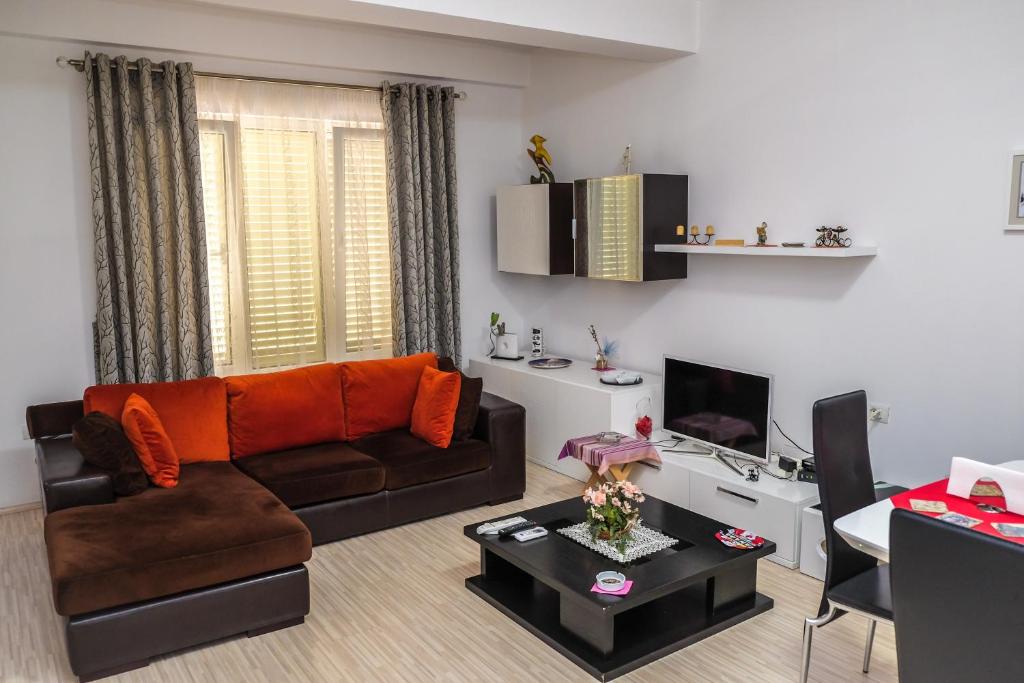 een woonkamer met een bank en een tv bij Ariadnes Apartments in Tirana