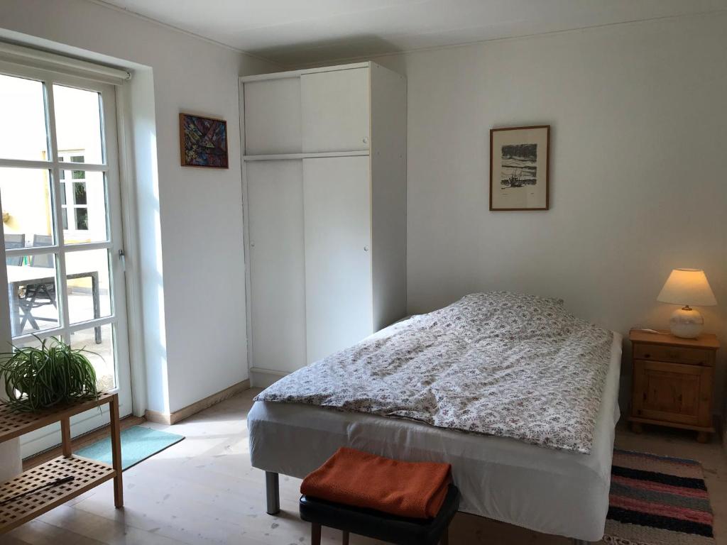 een witte slaapkamer met een bed en een raam bij Tranum Lys og Glas in Brovst