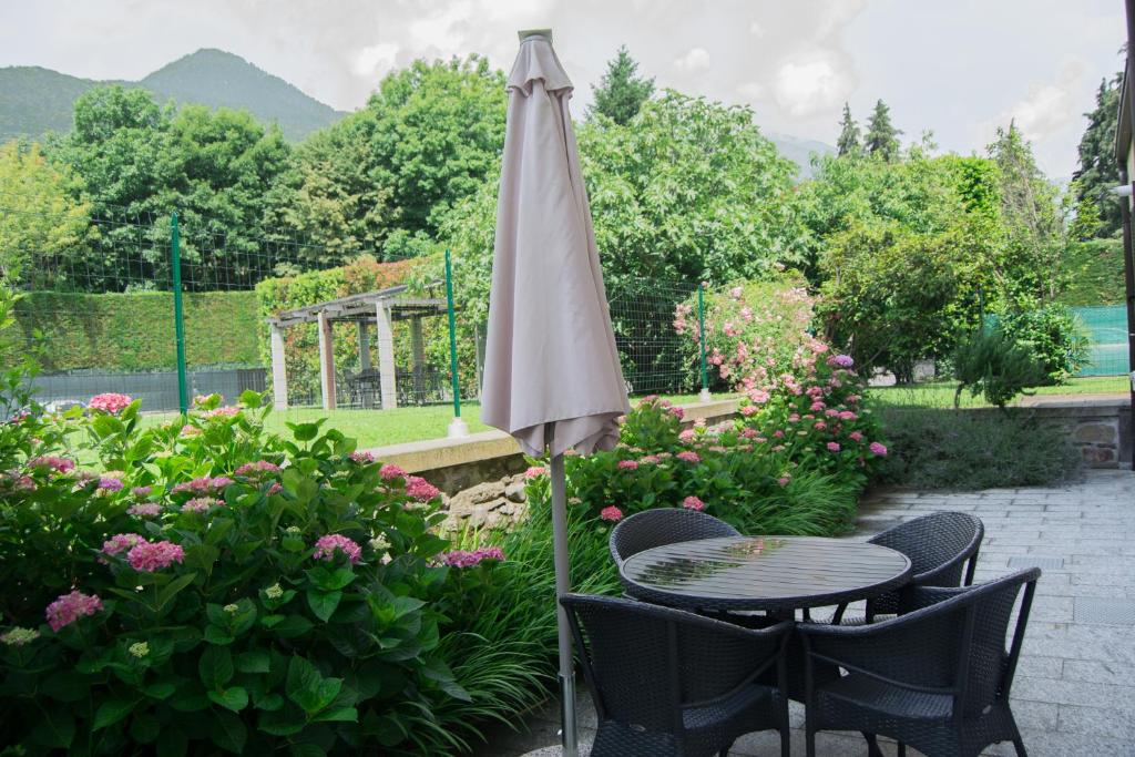 a table and chairs with an umbrella in a garden at Giardino delle Ortensie in Cannobio