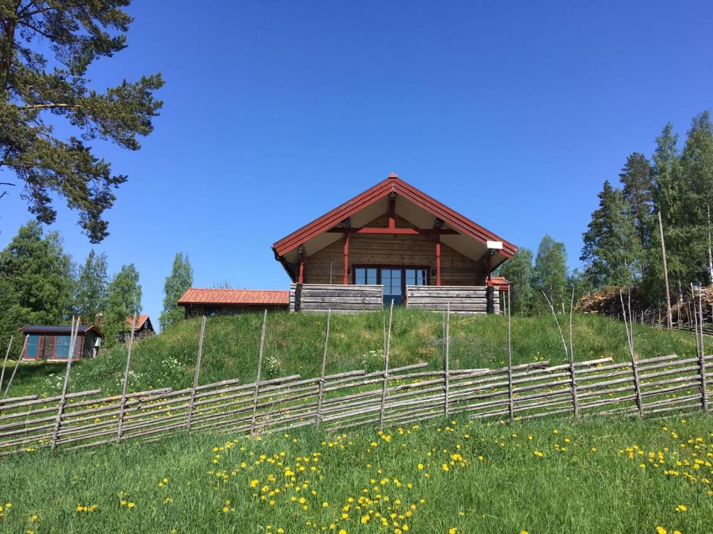 ein Haus auf einem Hügel mit einem Zaun in der Unterkunft Bergsäng Stuga in Leksands-Noret