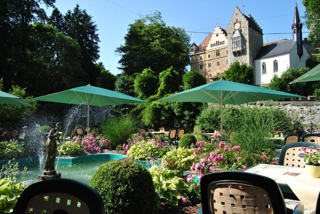 a garden with a fountain and green umbrellas at Schloss Egg in Bernried