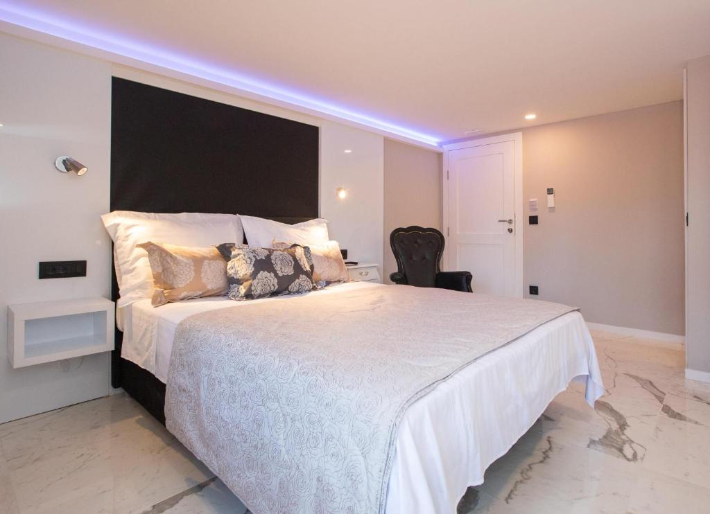 ein Schlafzimmer mit einem großen weißen Bett mit einem violetten Licht in der Unterkunft Soleil Luxury Rooms Old town in Dubrovnik