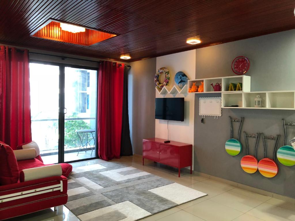 a living room with a red chair and a tv at Atlantis Residence in Melaka