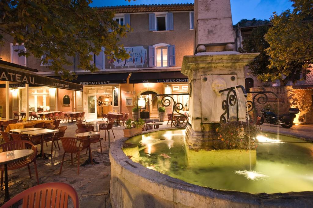 uma fonte num pátio em frente a um restaurante em Le Vieux Château em Aiguines