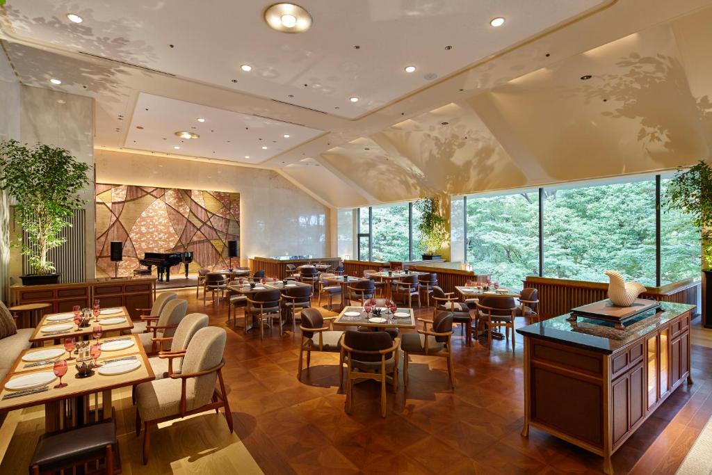 a restaurant with tables and chairs and a piano at Grand Prince Hotel Shin Takanawa in Tokyo