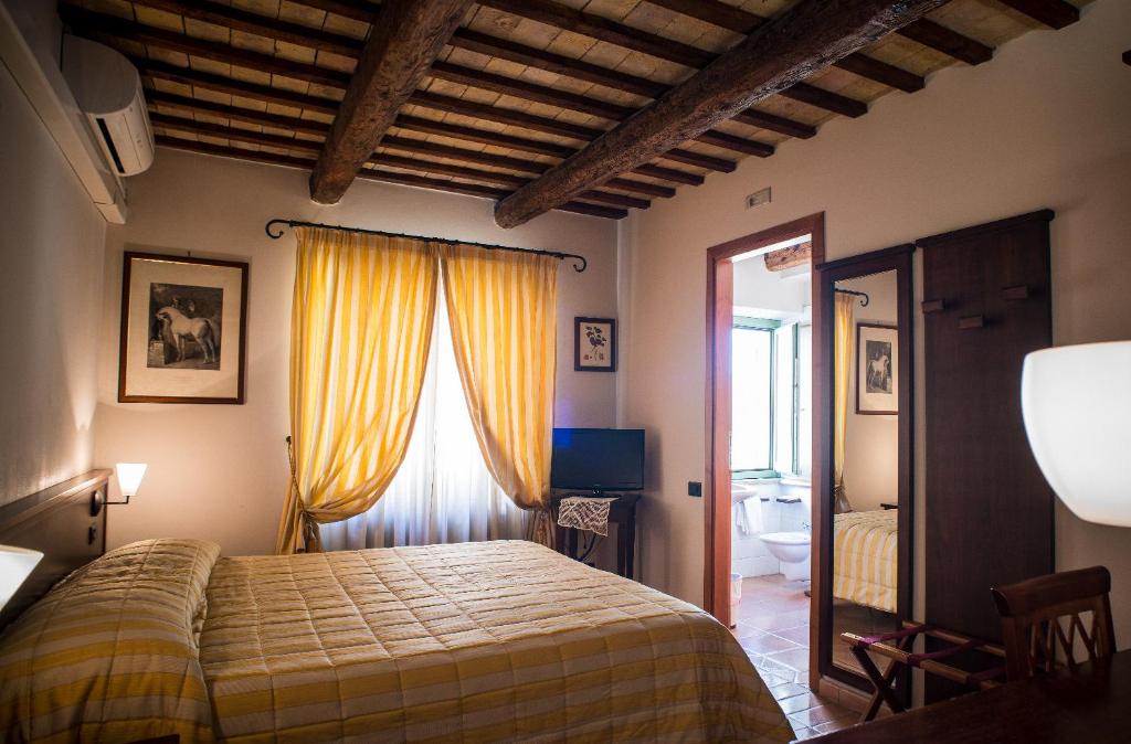 a bedroom with a bed and a window with yellow curtains at Hotel San Claudio in Corridonia