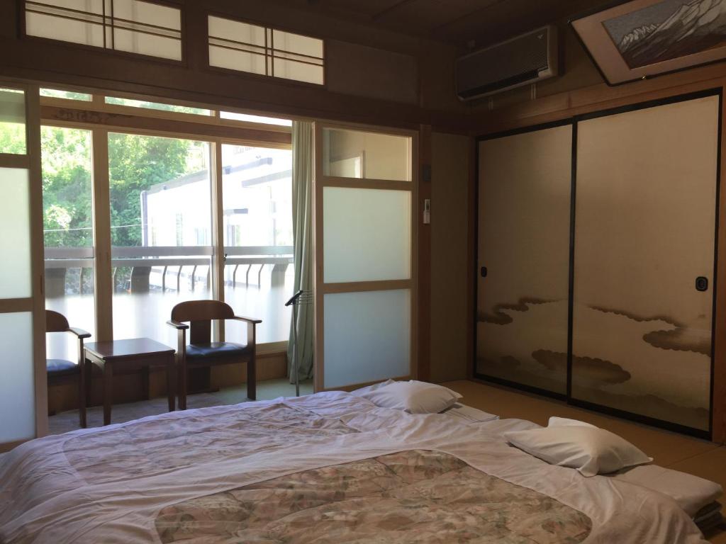 a bedroom with a bed and a large window at Daymaruya Ryokan in Yamanouchi